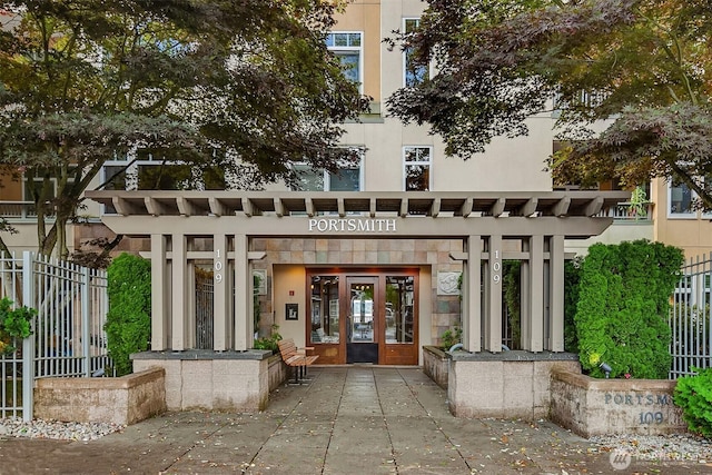 property entrance featuring fence, french doors, and stucco siding