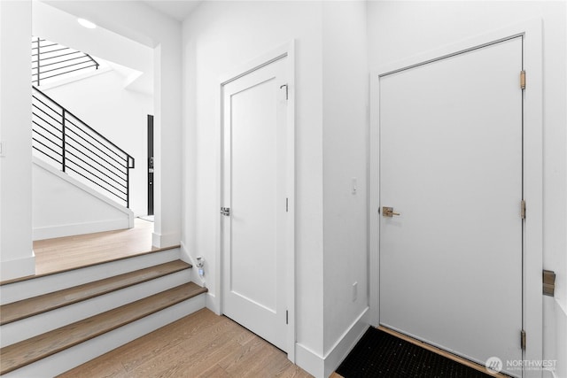 entrance foyer featuring baseboards, stairway, and wood finished floors