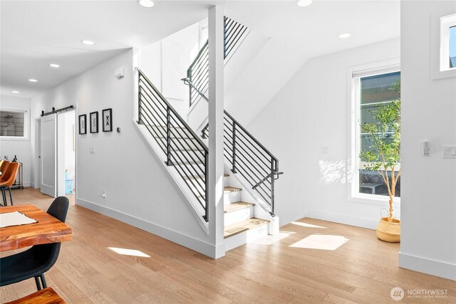 staircase with a barn door, baseboards, wood finished floors, and recessed lighting