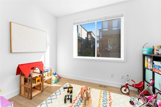 rec room featuring baseboards, visible vents, and wood finished floors