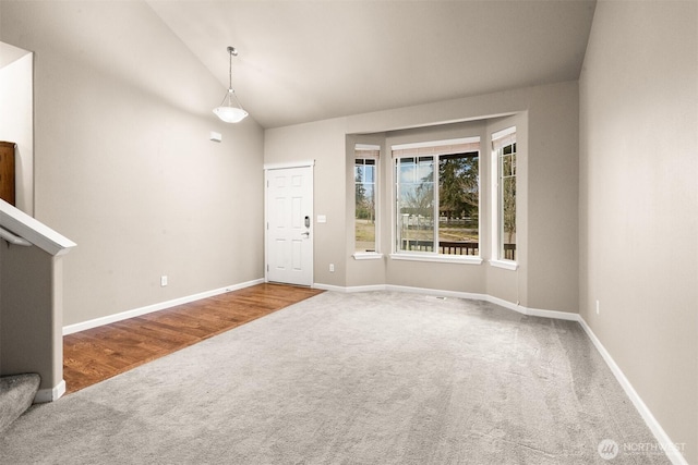 foyer entrance featuring carpet, vaulted ceiling, and baseboards