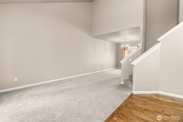 unfurnished room with baseboards, stairway, a chandelier, and wood finished floors