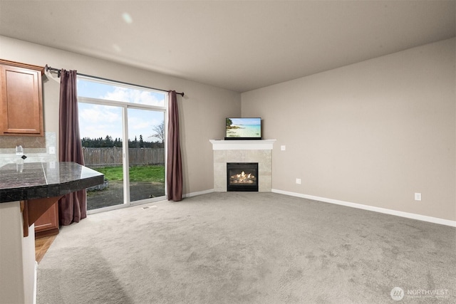 unfurnished living room with light colored carpet, a fireplace, and baseboards