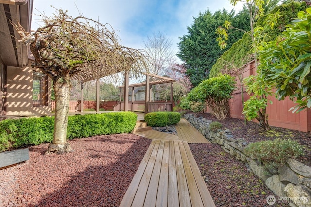 view of yard featuring a deck, a pergola, and a fenced backyard