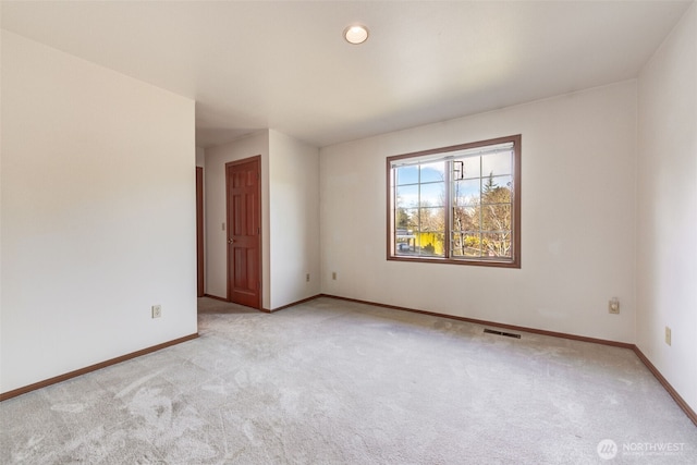 spare room featuring light colored carpet, visible vents, and baseboards