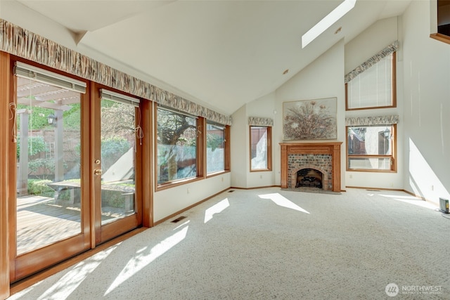 unfurnished living room with visible vents, high vaulted ceiling, a skylight, a fireplace, and baseboards