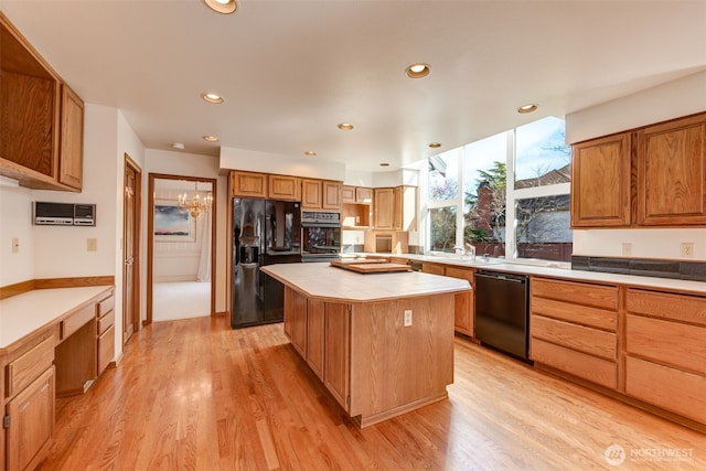 kitchen featuring tile countertops, light wood finished floors, recessed lighting, black appliances, and a center island