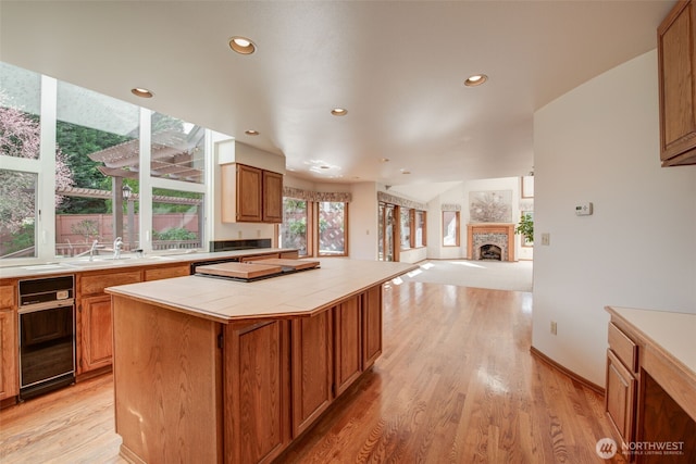 kitchen with a center island, tile countertops, recessed lighting, light wood-style floors, and a fireplace