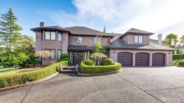 view of front facade featuring french doors, driveway, a garage, and a chimney