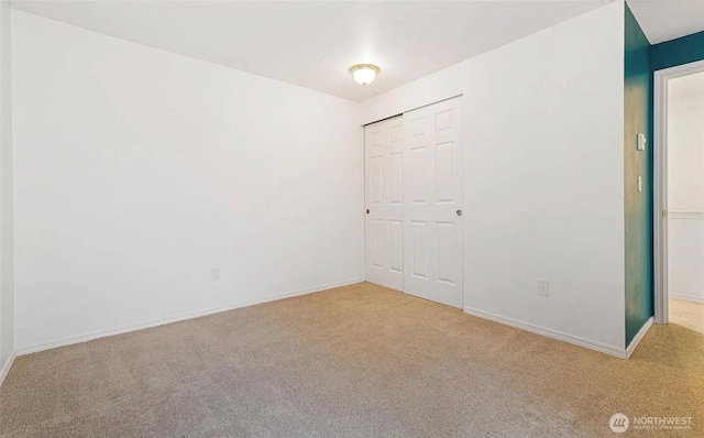 unfurnished bedroom with carpet, a closet, and baseboards