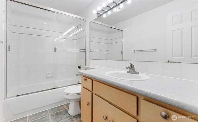 full bathroom with bath / shower combo with glass door, vanity, and toilet