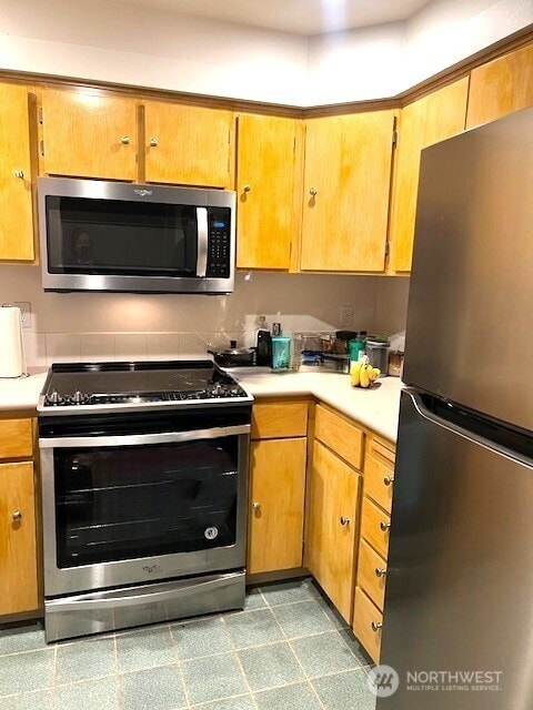 kitchen featuring appliances with stainless steel finishes, tile patterned floors, and light countertops