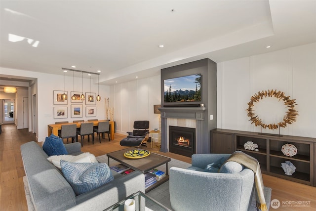 living area featuring recessed lighting, a fireplace with flush hearth, and wood finished floors