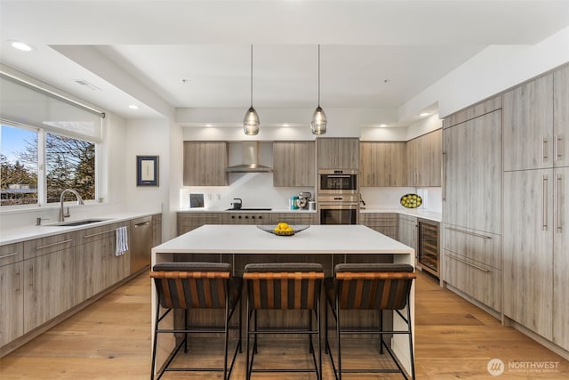 kitchen featuring a kitchen bar, modern cabinets, a sink, wine cooler, and wall chimney range hood