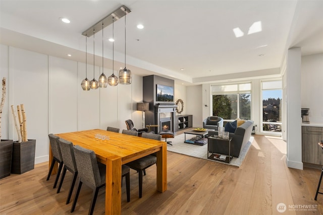 dining area with recessed lighting, light wood-type flooring, and a lit fireplace