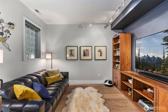 living room featuring wood finished floors, visible vents, and baseboards