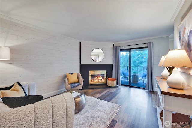 living area featuring crown molding, baseboards, wood finished floors, and a glass covered fireplace