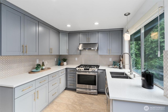 kitchen with under cabinet range hood, gray cabinets, stainless steel gas range, and a sink