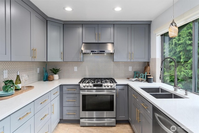 kitchen with a sink, gray cabinetry, light countertops, stainless steel appliances, and under cabinet range hood