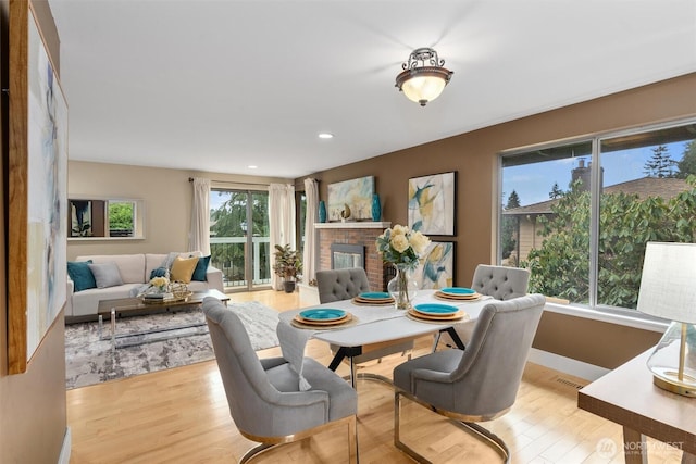 dining area featuring recessed lighting, baseboards, a fireplace, and light wood finished floors