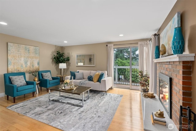 living area with recessed lighting, light wood-style floors, and a brick fireplace