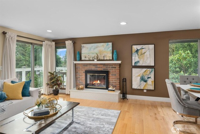 living room featuring recessed lighting, baseboards, a brick fireplace, and wood finished floors