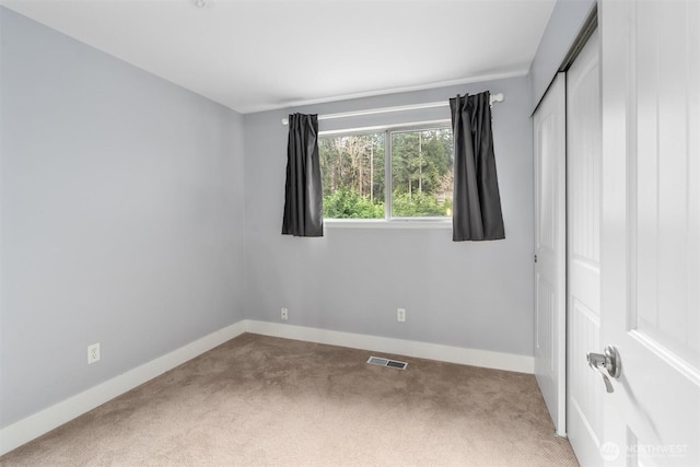 unfurnished bedroom with visible vents, baseboards, a closet, and carpet flooring