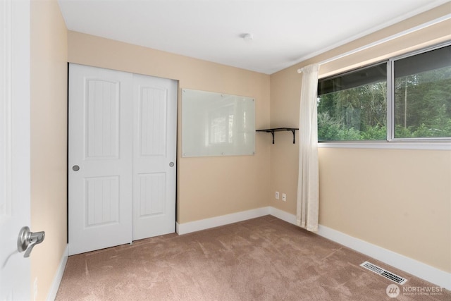 unfurnished bedroom featuring visible vents, carpet floors, baseboards, and a closet