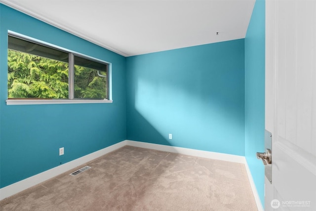 empty room featuring carpet, visible vents, and baseboards