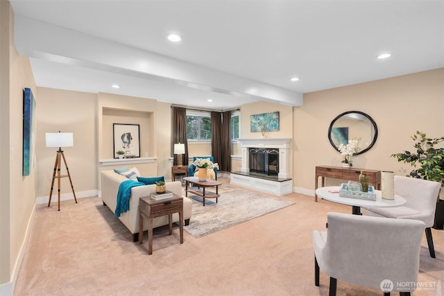 living room with recessed lighting, a fireplace with raised hearth, baseboards, and light carpet