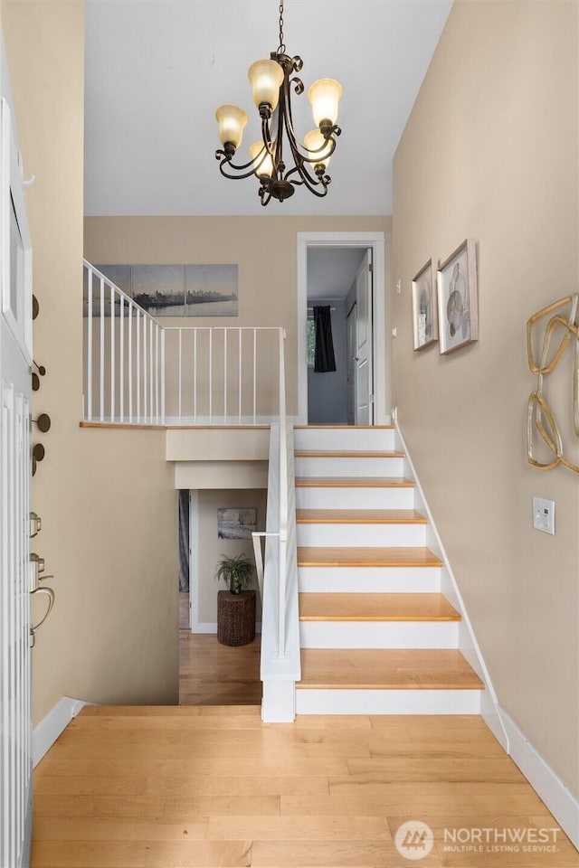 stairs with a chandelier, baseboards, and wood finished floors