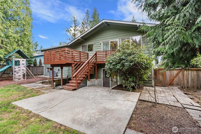 rear view of property featuring a wooden deck, a fenced backyard, stairs, a playground, and a patio area