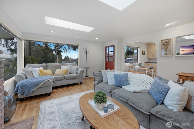 living area featuring a skylight, light wood-style flooring, and recessed lighting