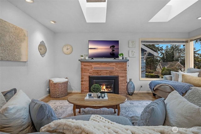 living area featuring recessed lighting, a skylight, wood finished floors, baseboards, and a brick fireplace