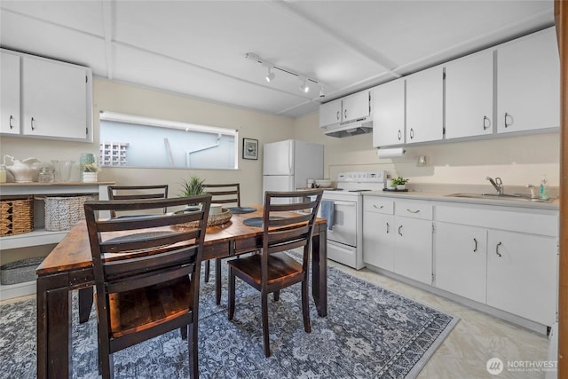 kitchen featuring white appliances, under cabinet range hood, white cabinetry, and a sink