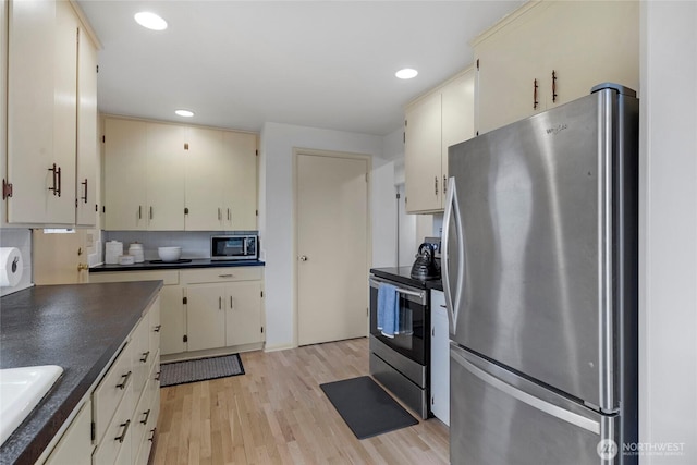 kitchen with dark countertops, appliances with stainless steel finishes, light wood-type flooring, backsplash, and recessed lighting