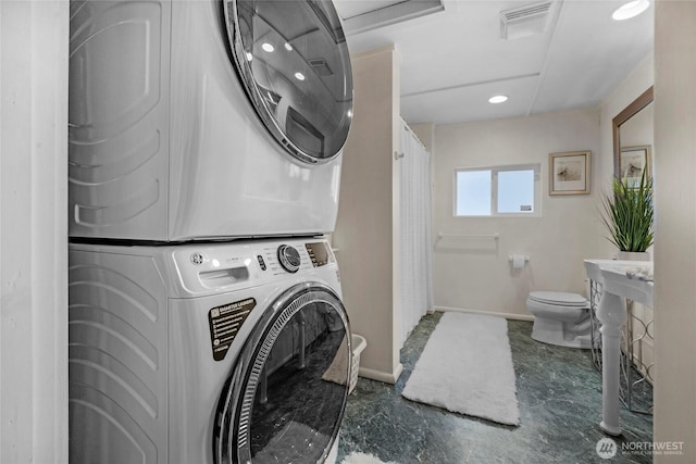 washroom featuring baseboards, visible vents, and stacked washer / drying machine