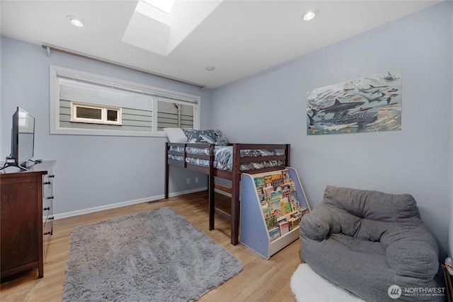 bedroom with recessed lighting, a skylight, light wood-style flooring, and baseboards