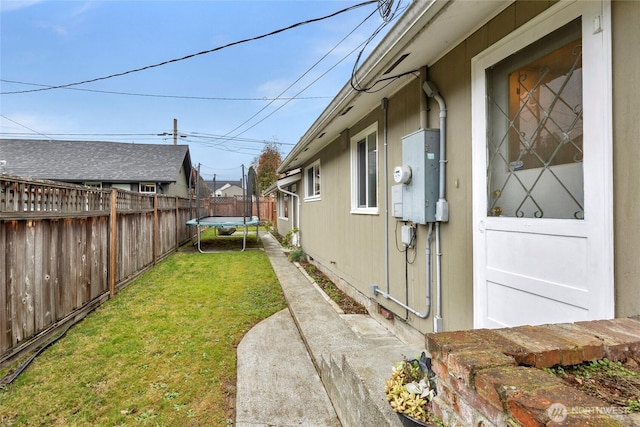 view of yard featuring a trampoline, a patio area, and fence