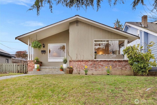 view of front of property with brick siding, a front lawn, and fence