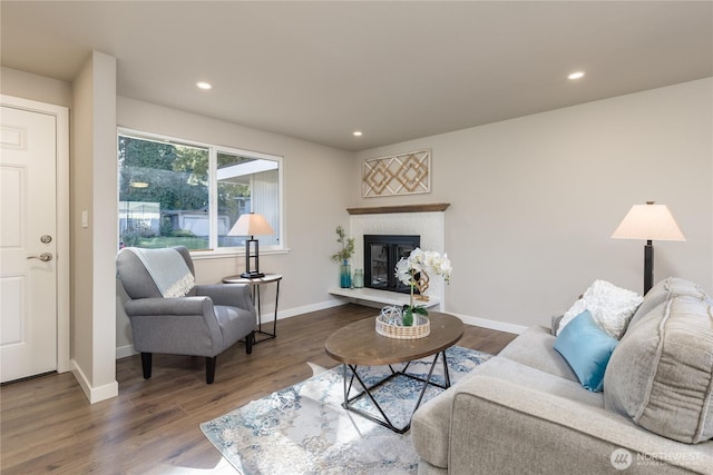 living area featuring a brick fireplace, wood finished floors, and recessed lighting