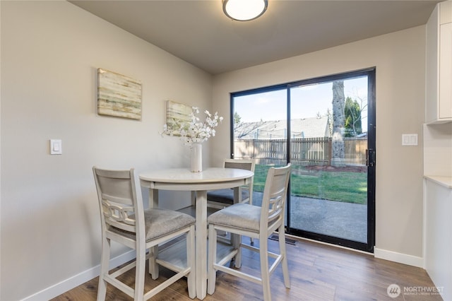 dining space featuring baseboards and wood finished floors