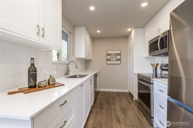 kitchen with dark wood-style floors, tasteful backsplash, appliances with stainless steel finishes, white cabinets, and a sink