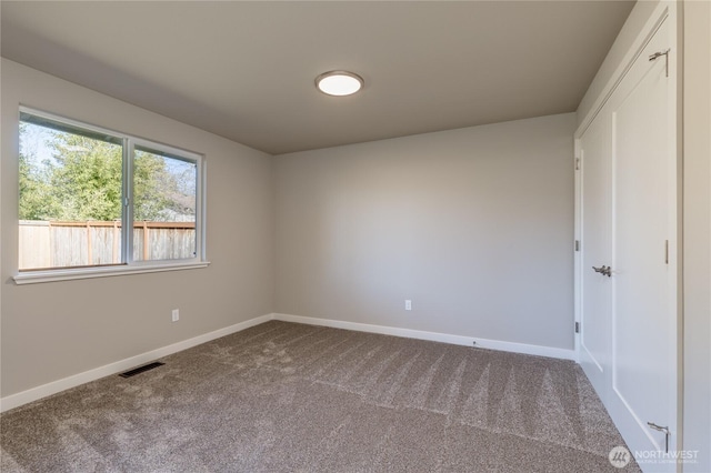 unfurnished bedroom featuring baseboards, visible vents, and dark carpet