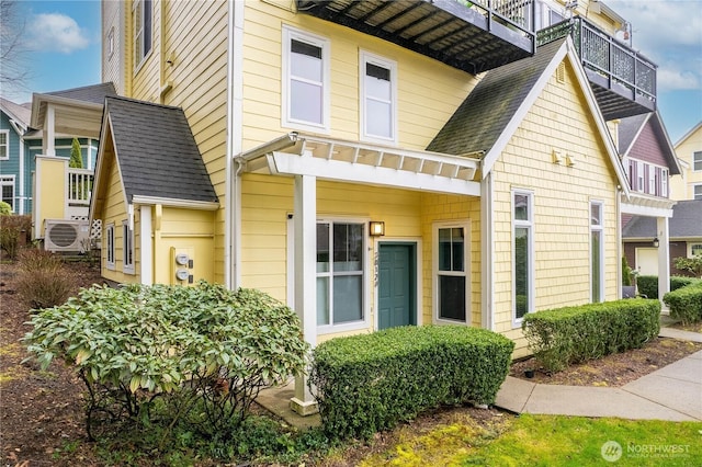 exterior space featuring ac unit and roof with shingles