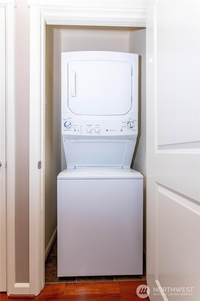 laundry room with wood finished floors, stacked washer and clothes dryer, and laundry area