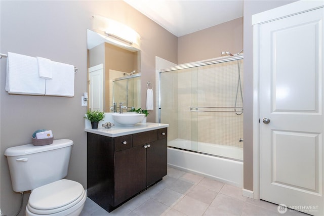 bathroom with toilet, bath / shower combo with glass door, vanity, and tile patterned floors