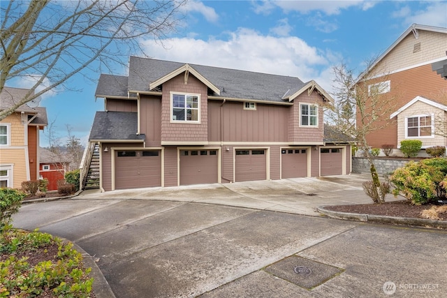 view of front of home with stairs, a shingled roof, board and batten siding, and a garage