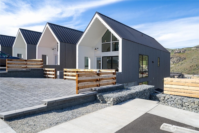 modern farmhouse with a patio area, fence, and metal roof