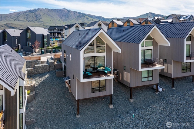 back of house featuring a standing seam roof, a mountain view, and metal roof